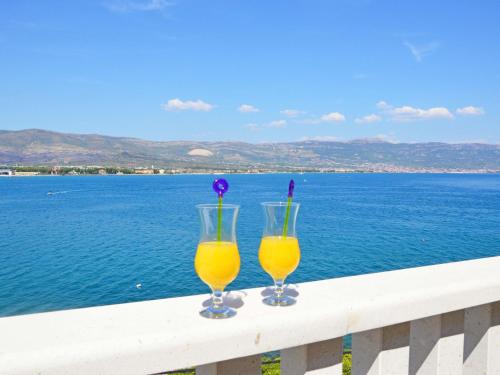 due bicchieri di succo d'arancia seduti su una ringhiera con vista sull'oceano di Apartment Mornar-1 by Interhome a Trogir