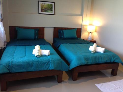 2 camas en una habitación con sábanas azules y almohadas blancas en The City House, en Krabi