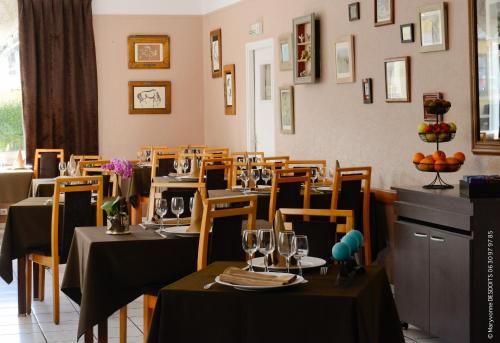 ein Restaurant mit Tischen und Stühlen mit Weingläsern in der Unterkunft Logis Hôtel Restaurant de France in Isigny-sur-Mer