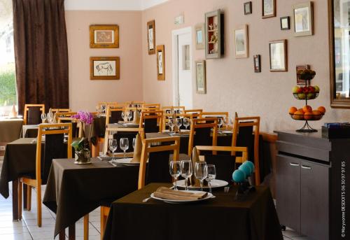 a restaurant with tables and chairs with wine glasses at Logis Hôtel Restaurant de France in Isigny-sur-Mer