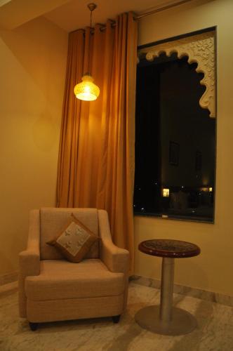 a living room with a chair and a table at Regenta Central Mewargarh, Near Biological park in Udaipur