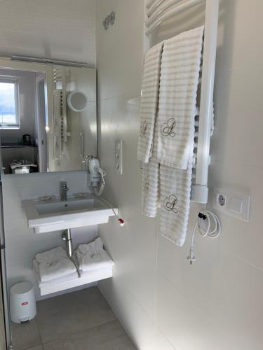 een badkamer met een wastafel, een spiegel en handdoeken bij Hostal Antolín in Redondela