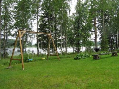 um velho balanço num campo de relva com um lago em Holiday Home Helmiranta by Interhome em Saarijärvi
