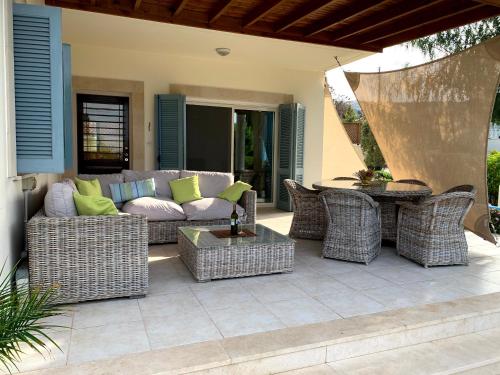 a patio with a couch and chairs and a table at Beach villa Gladiolus in Neo Chorio