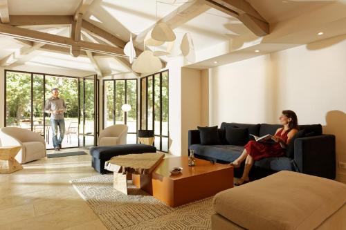 a woman sitting on a couch in a living room at Domaine du Buc , les Gîtes de Prestige in Marssac-sur-Tarn