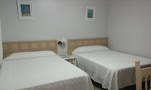 a hotel room with two beds and a television at Hostal Antolín in Redondela