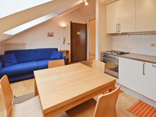a kitchen and dining room with a table and a blue couch at Apartment Enrosadira-4 by Interhome in Alba di Canazei