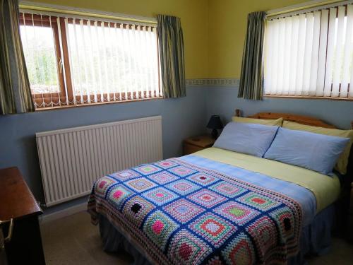 a bedroom with a bed with a colorful quilt at Cae y Rhedyn Annexe in Crickhowell