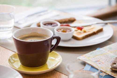 a cup of coffee on a table with a plate of food at ibis Styles Athens Routes in Athens