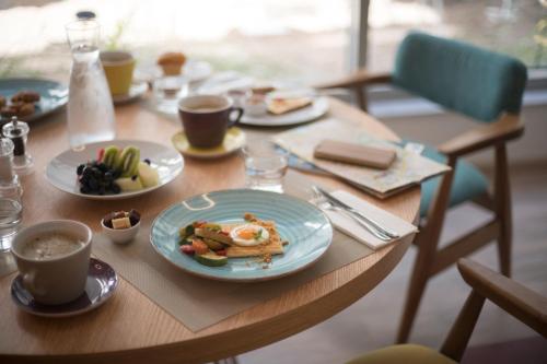 a wooden table with plates of food and cups of coffee at ibis Styles Athens Routes in Athens