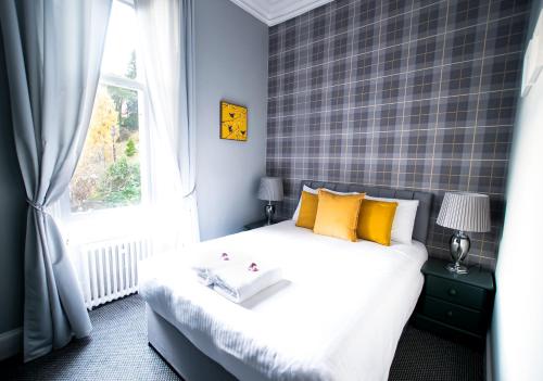 a bedroom with a bed with yellow pillows and a window at McInnes House rooms with breakfast in Kingussie