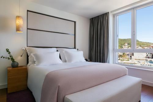 a bedroom with a large bed with a large window at Adriana Hvar Spa Hotel in Hvar