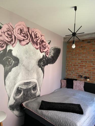 a mural of a cow with roses on a wall at Siedlisko Kępina Zdrój in Ostrów