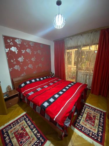 a bedroom with a red bed with red curtains and two rugs at Friend's House in Piteşti