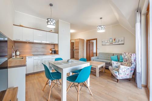 a kitchen and living room with a table and chairs at Rezydencja Park, Sun & Snow in Mielno