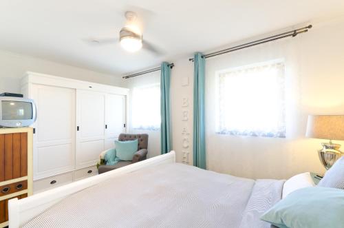 Schlafzimmer mit einem Bett, einem TV und einem Stuhl in der Unterkunft Ostseestrandliebe Villa Sanddorn Nr2 in Börgerende-Rethwisch