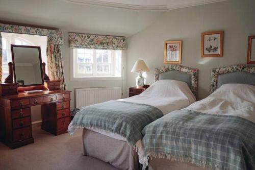 a bedroom with two beds and a dresser and a mirror at Garden Cottage, Fochabers in Fochabers