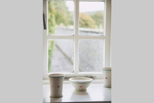 ein Fenster mit drei Tassen auf einem Tisch in der Unterkunft Garden Cottage, Fochabers in Fochabers