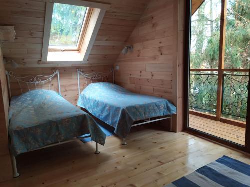 two beds in a room with two windows at Domek Moczykija in Szypliszki