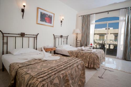 a hotel room with two beds and a large window at Bella Vista Resort Hurghada Families And Couples Only in Hurghada