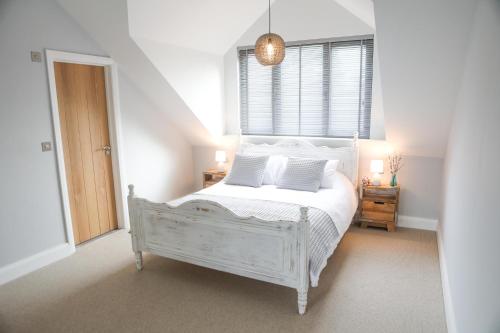 a bedroom with a white bed and a window at The Harbour Retreat in Birdham