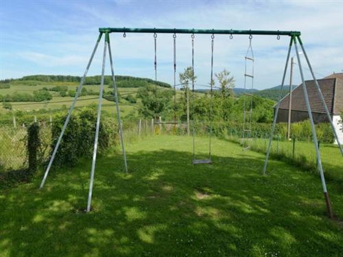 an empty swing set in a field of grass at Gîte de Bellevue avec piscine intérieure privative in Bergesserin