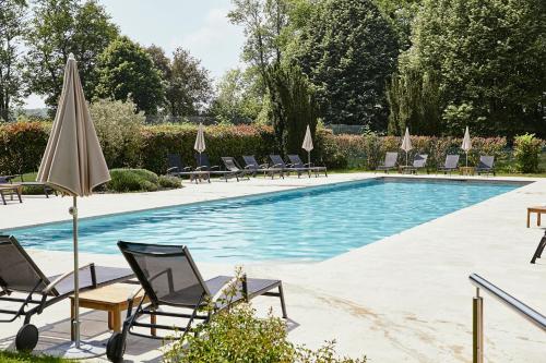 une piscine avec chaises longues et parasols dans l'établissement Château De Villiers-Le-Mahieu, à Villiers-le-Mahieu