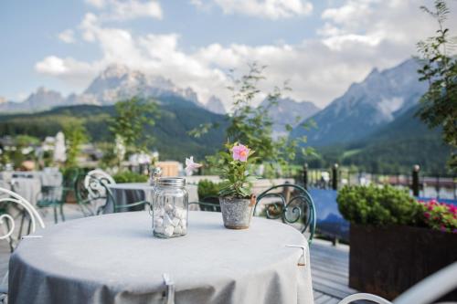 a table with a flower in a glass jar on it at Berghotel - Sexten in Sesto