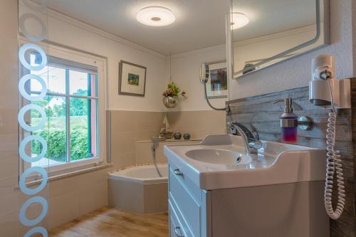 ein Badezimmer mit einem Waschbecken, einem Spiegel und einer Badewanne in der Unterkunft Elbschlösschen Refugium in Pirna