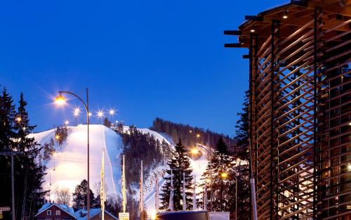a city with a snow covered mountain at night at Hotel Himos in Jämsä