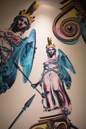 a statue of a woman with an umbrella on a wall at ibis Styles Athens Routes in Athens