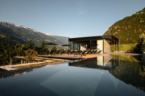 a building with a pool of water next to a mountain at Design Hotel Tyrol in Rablà