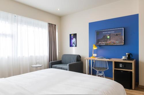 a hotel room with a bed and a chair and a tv at ibis Styles Athens Routes in Athens