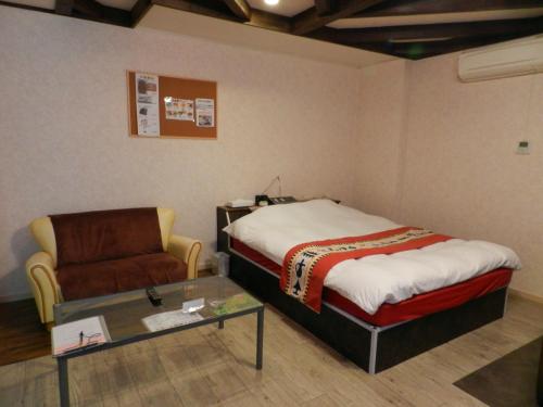 a bedroom with a bed and a couch and a glass table at Hotel Mariage Tsukuba in Tsukuba