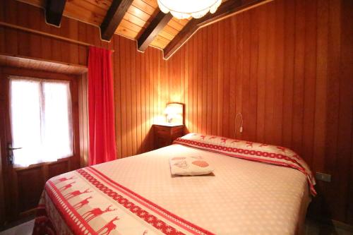 a bedroom with a bed with a red and white blanket at Appartamento Il Camoscio - Affitti Brevi Italia in Brusson