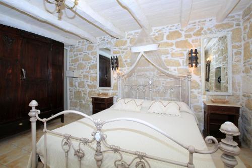 a bedroom with a white bed and a stone wall at Villa Oasis in Kamilari