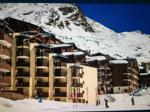 a building in the snow in front of a mountain at Les temples du soleil in Val Thorens