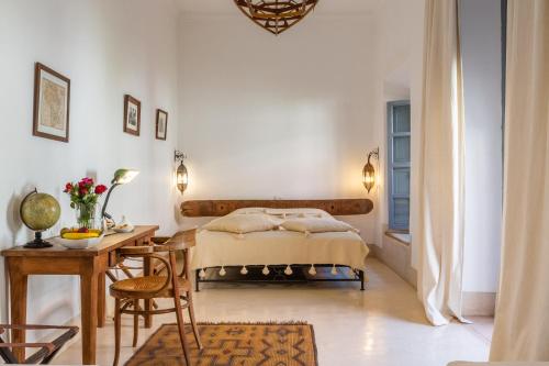 a bedroom with a bed and a table and a desk at Riad Tchaikana in Marrakech