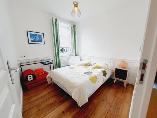 Cette chambre comprend un lit avec des draps blancs et du parquet. dans l'établissement Les Sablons - Très Bel Appartement , Lumineux, à Saint-Malo