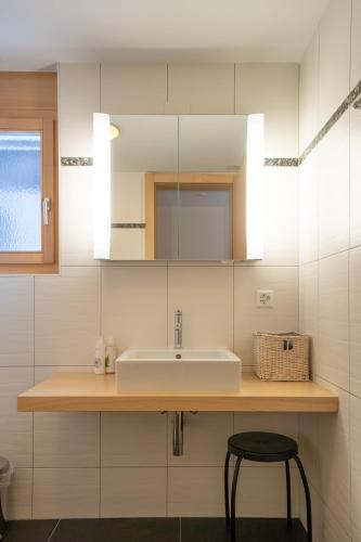 a white bathroom with a sink and a stool at Jessica 2 in Saas-Fee