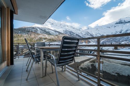 een balkon met een tafel en stoelen en met sneeuw bedekte bergen bij Jessica 2 in Saas-Fee