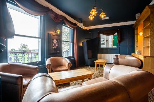 a waiting room with leather furniture and a table at Manor House Hotel Holy Island in Berwick-Upon-Tweed