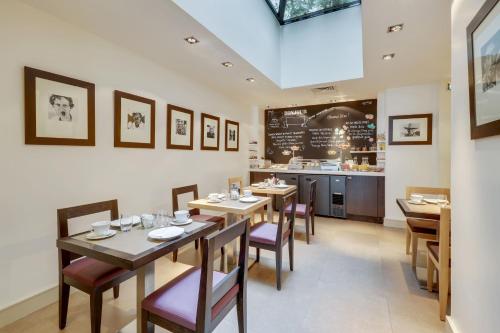 un restaurant avec des tables et des chaises en bois et un comptoir dans l'établissement Hotel Duret Paris Champs Elysées, à Paris