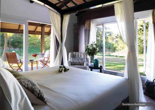 a bedroom with a large white bed and windows at The Serai Kabini in Begūr