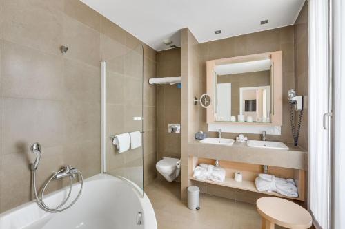 y baño con bañera, aseo y lavamanos. en Hotel Duret Paris, en París