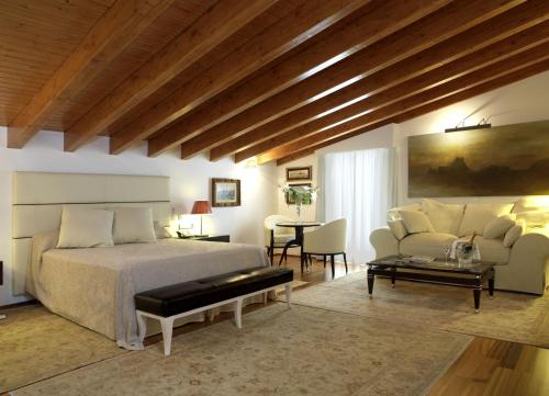 a bedroom with a bed and a couch and a table at Mirador de Dalt Vila-Relais & Chateaux in Ibiza Town