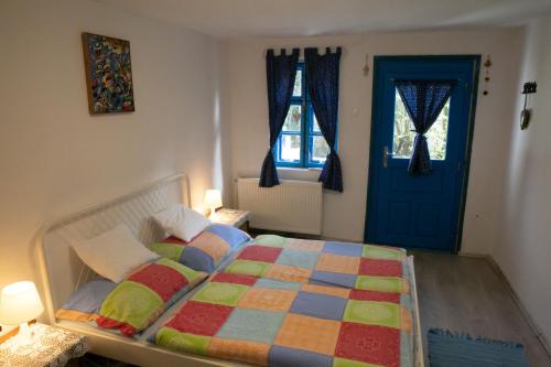a bedroom with a bed and a blue door at Kékfestő Vendégház in Bükkszentkereszt