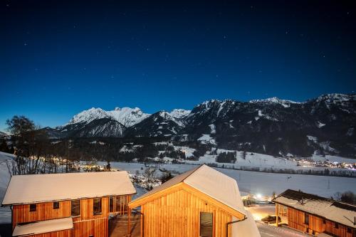 a ski lodge with snow covered mountains in the background at Bergresort Hauser Kaibling by ALPS RESORTS in Haus im Ennstal