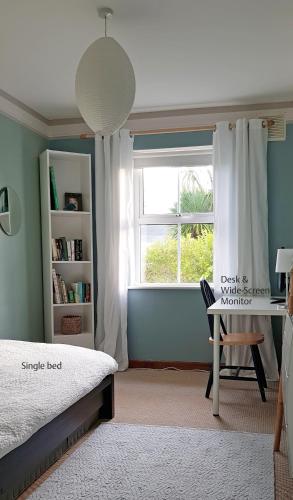 a bedroom with a bed and a desk and a window at Ula Cottage in Saint Helens