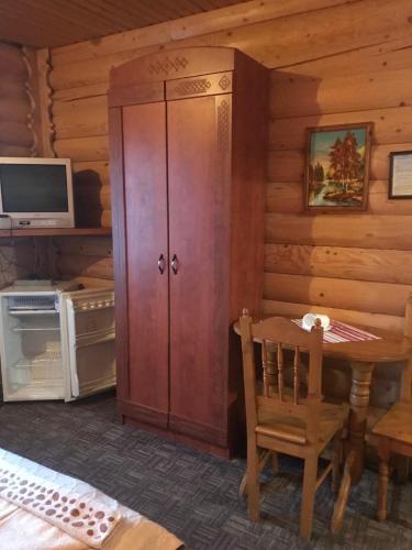 a wooden cabinet in a room with a table and a tv at Panorama Karpat in Yablunytsya